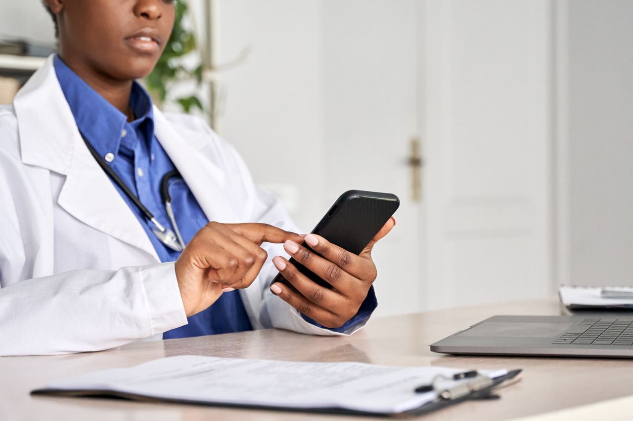 Ärztin überprüft digitale Gesundheitsdaten auf ihrem Smartphone im Büro.