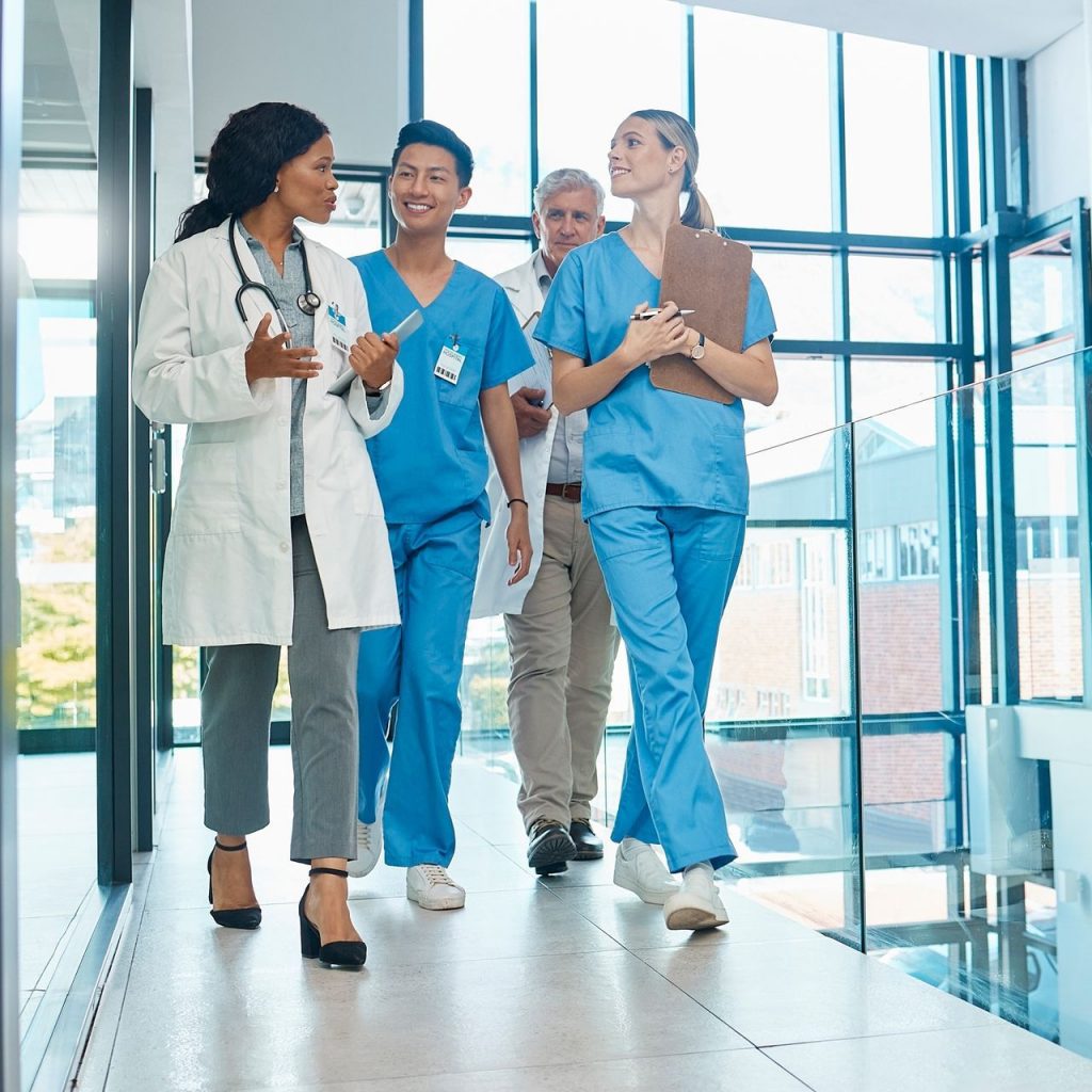 Medizinische Fachkräfte, darunter Ärzte und Pfleger, im Austausch auf dem Korridor eines modernen Krankenhauses.